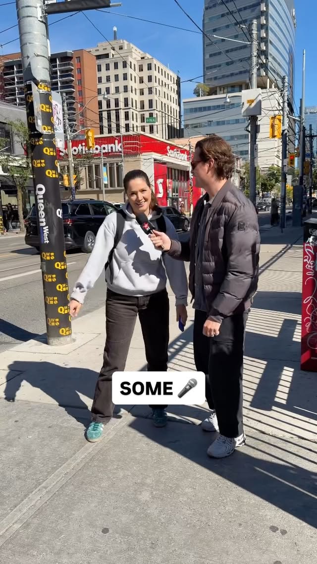 Myles hands a microphone to a passerby on a Toronto street